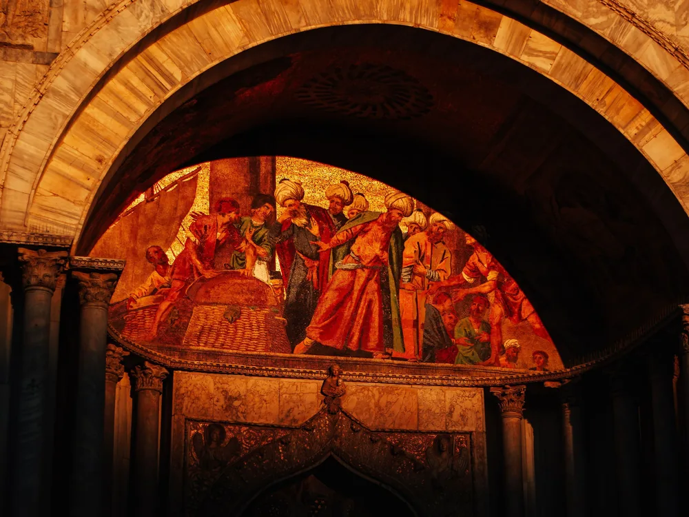 Mosaic scene glowing gold inside an archway of St Mark's Basilica